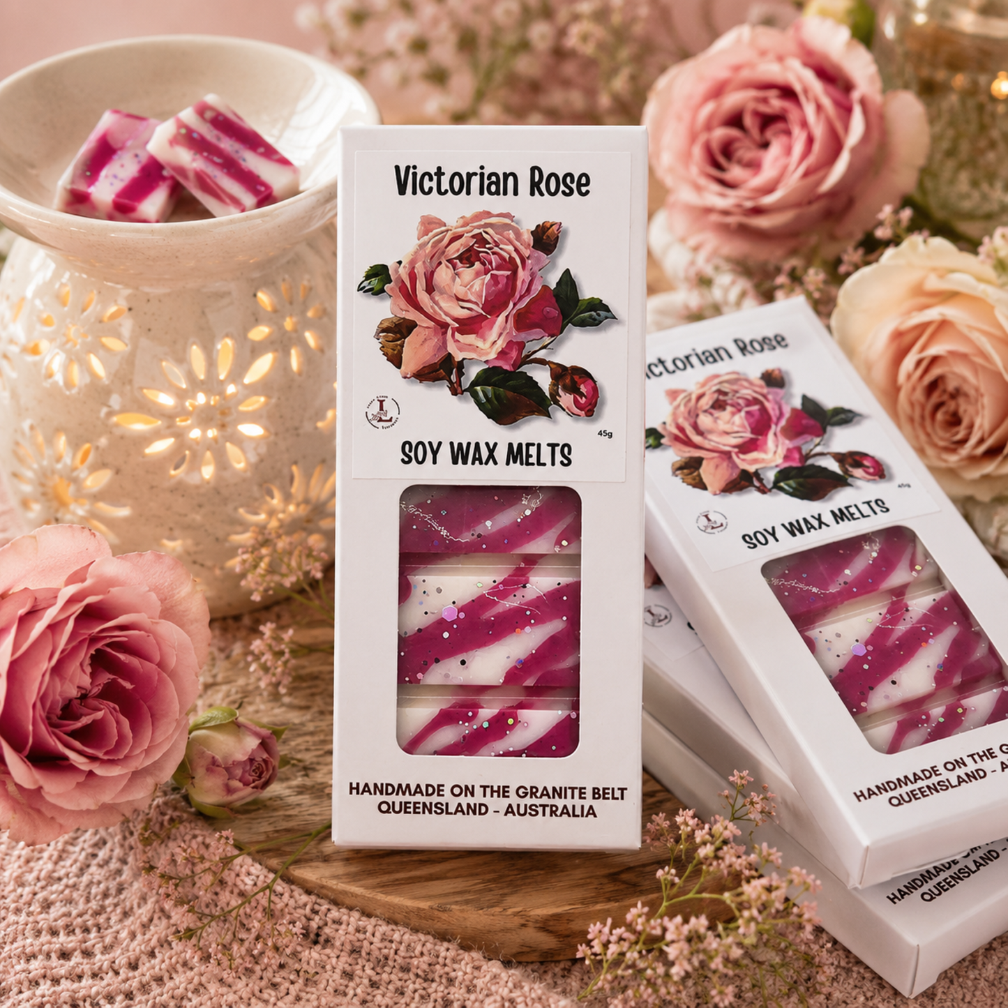 Handmade Victorian Rose premium soy wax melts by Lee's Little Luxuries in a 45g gift box featuring elegant vintage rose artwork, displayed beside a glowing ceramic wax warmer, fresh pink roses and delicate floral décor. Australian-made natural soy wax melts with a luxurious floral rose fragrance, perfect for creating a romantic, elegant and relaxing home atmosphere.